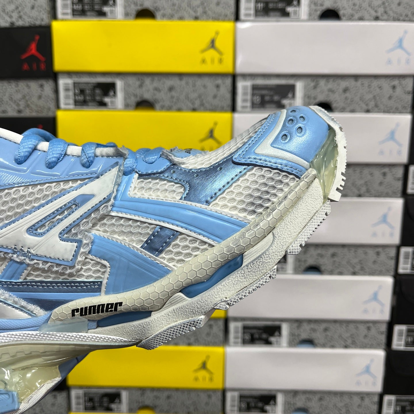Blue and white athletic sneaker, close-up side profile with chunky tread sole