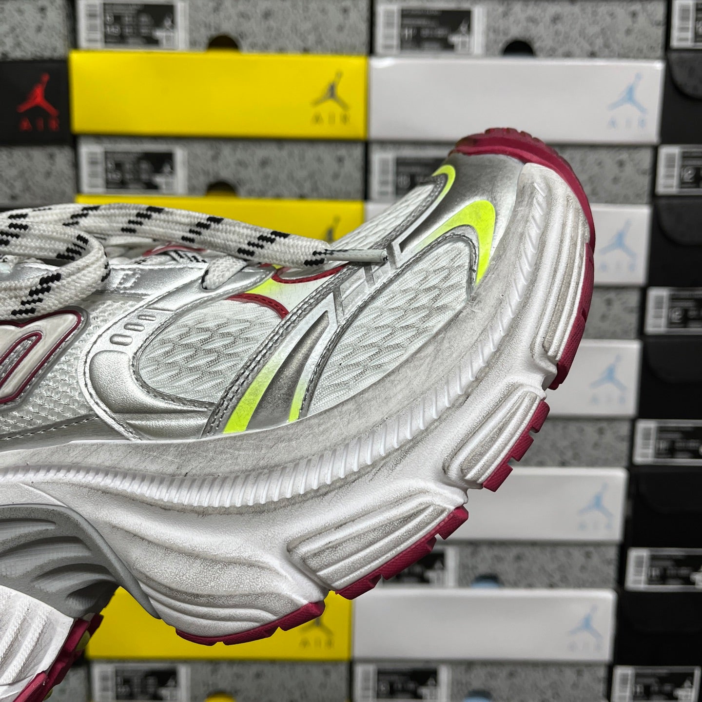 Silver sneaker side view with red lining and green-yellow accent panel details.