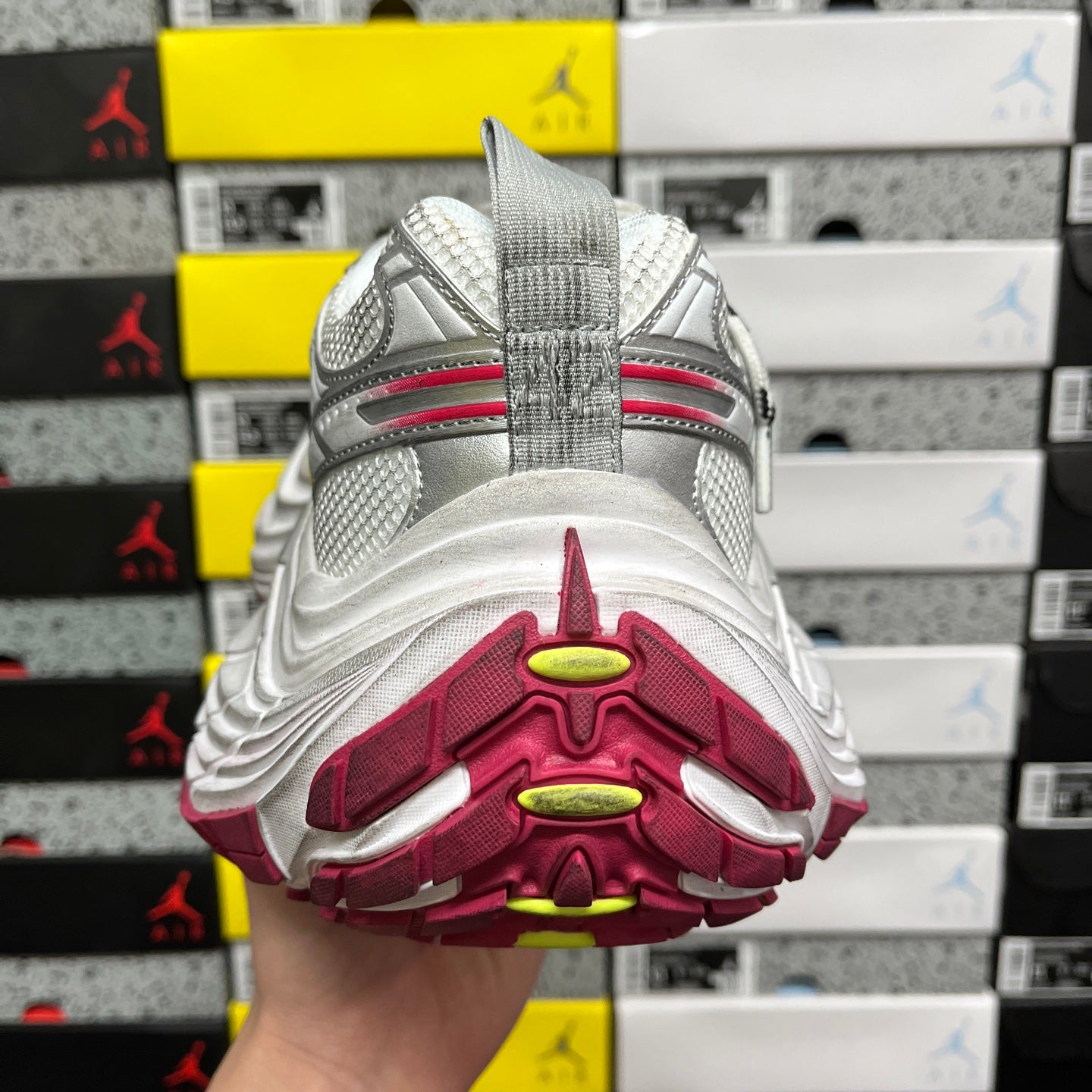 Shoe heel sole with burgundy tread pods and green-yellow highlights.