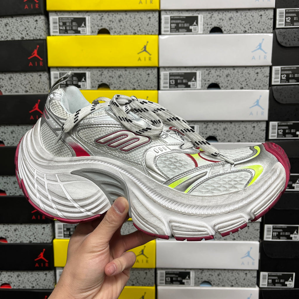 Silver athletic sneaker with red and green accents, lace-up and chunky sole.
