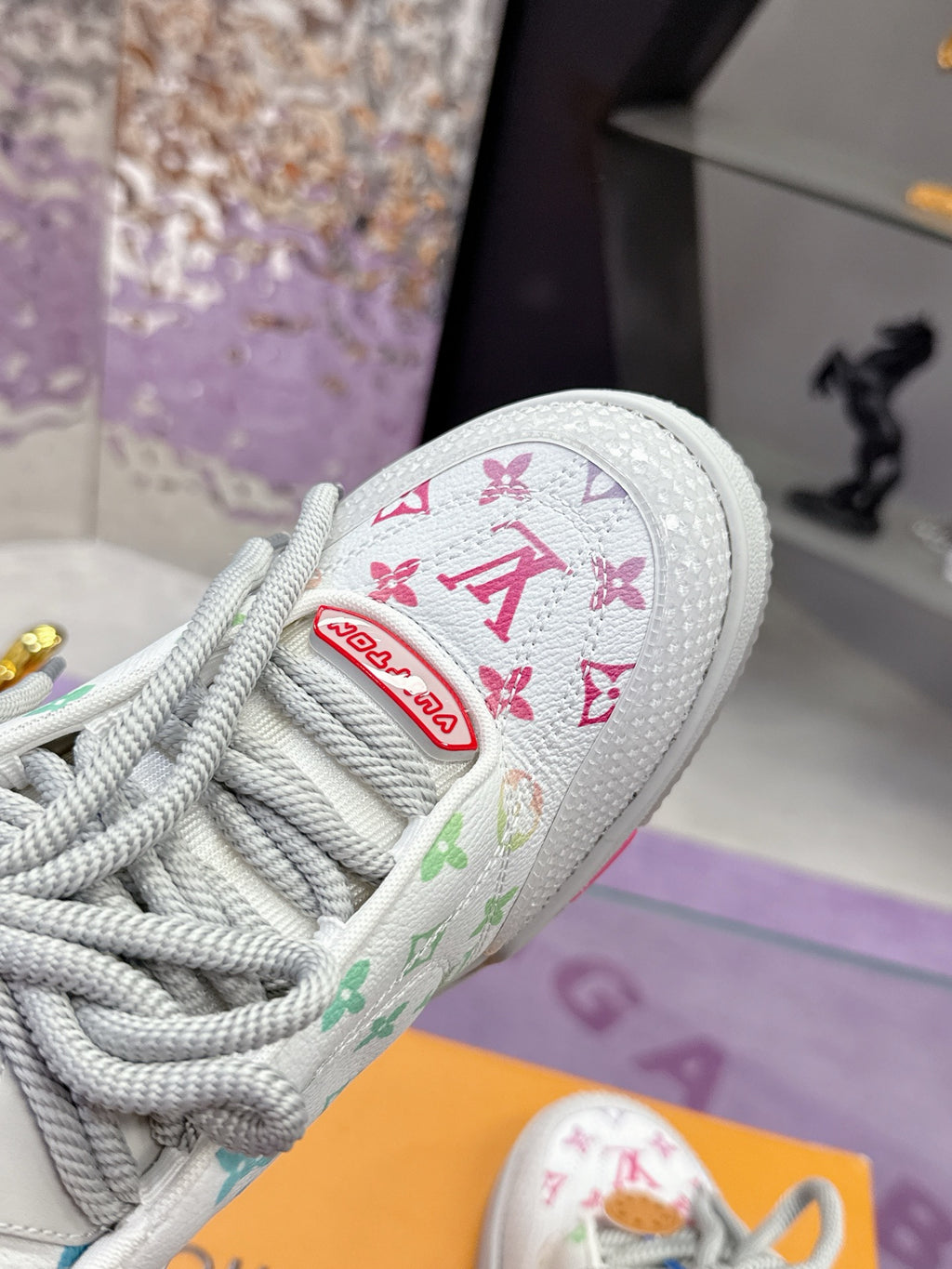 Louis Vuitton ladies sneaker close-up, white canvas with multicolor logo patch and laces