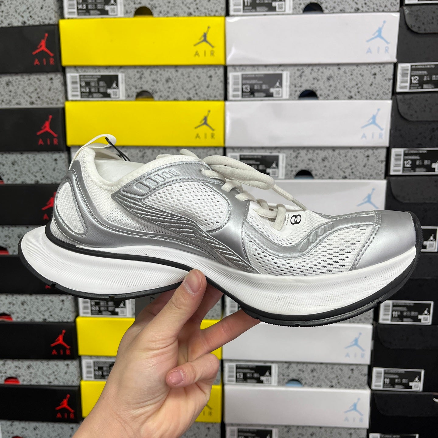 Silver and white mesh lace-up sneaker in side profile with black outsole.