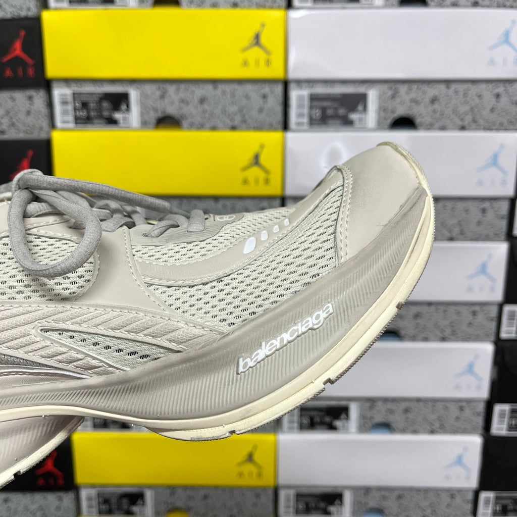 Off-white lace-up running shoe with curved side branding and ribbed sole edge