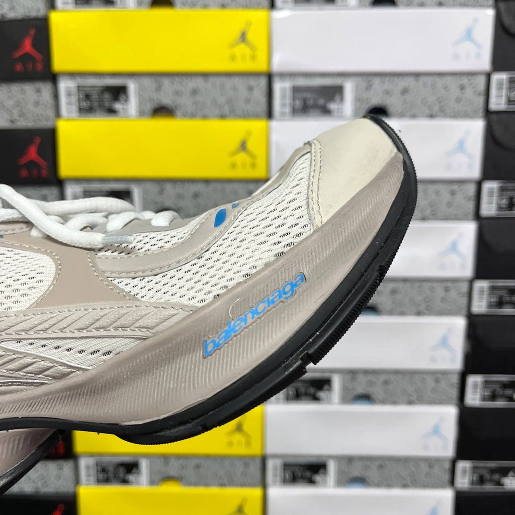 Balenciaga unisex sneakers in light beige with blue logo detail on side, angled view