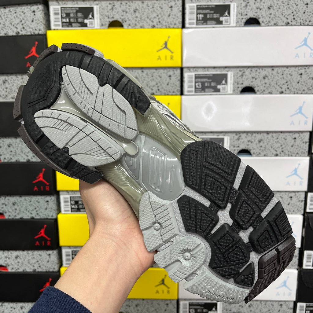 Gray sneaker outsole with patterned traction tread and molded cushioning pads.