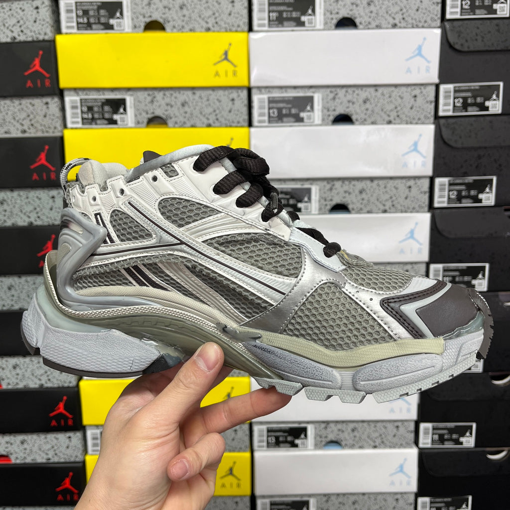 White and gray unisex sneaker with black laces, mesh panels, and cushioned sole.