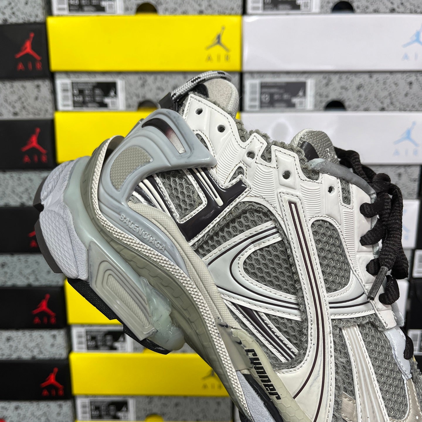 White and gray sneaker with black laces, stitched trims, and thick protective sole.