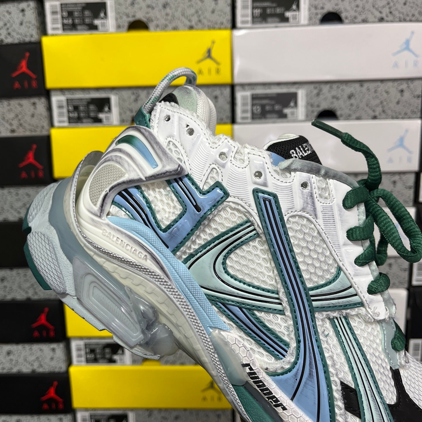 Runner sneaker top view with white mesh, teal stripe detailing, green laces, thick sole.