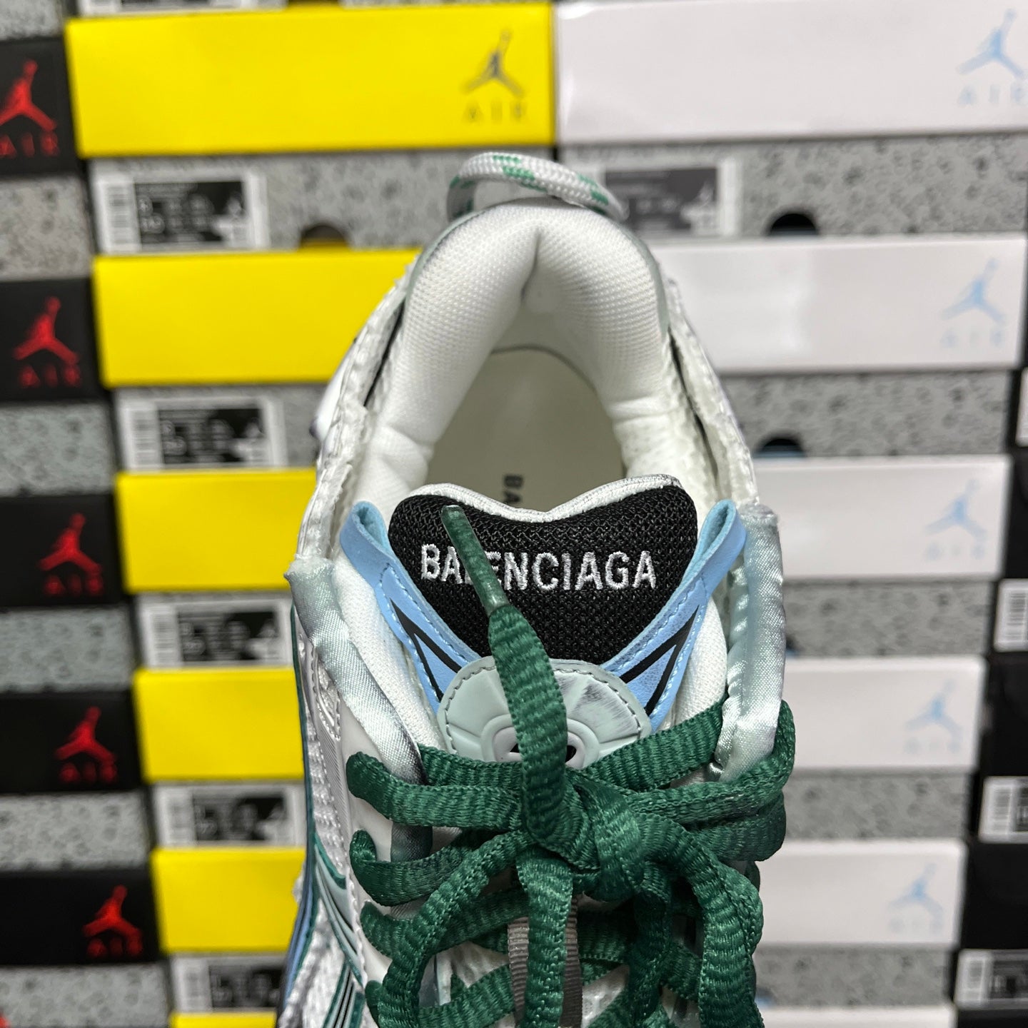 Runner sneaker heel with Balenciaga label, white lining, green laces, teal accents.