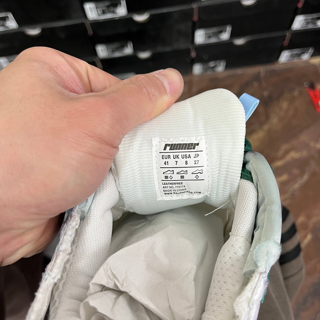 Runner sneaker interior showing size label on white knit lining with green lace loops.