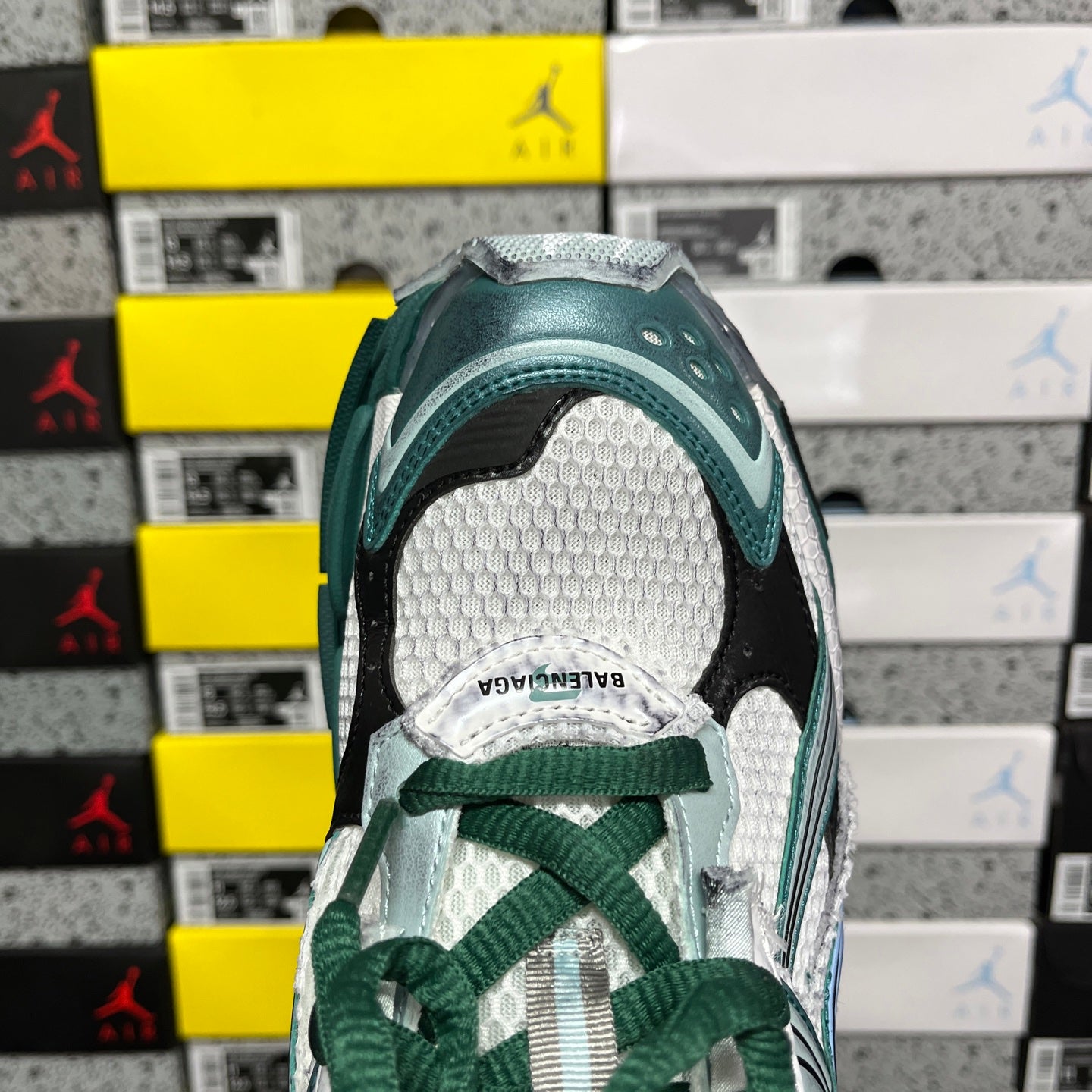 Runner sneaker heel opening with white lining and green lace tie detail, close-up.