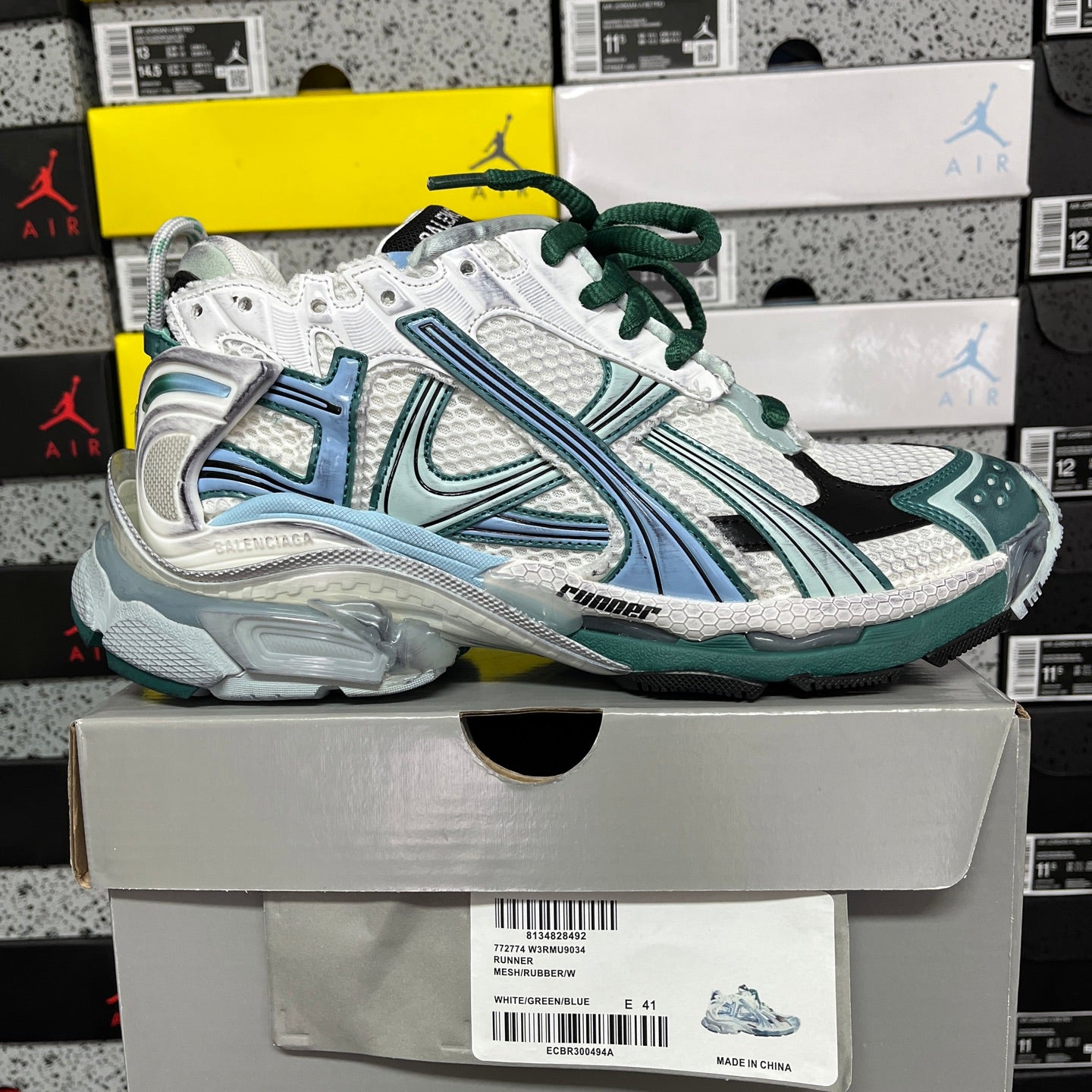 Runner sneaker side view with white upper, teal paneling, green laces, thick sole.