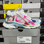 White lace-up sneakers with blue, red, and pink side stripes and chunky sole