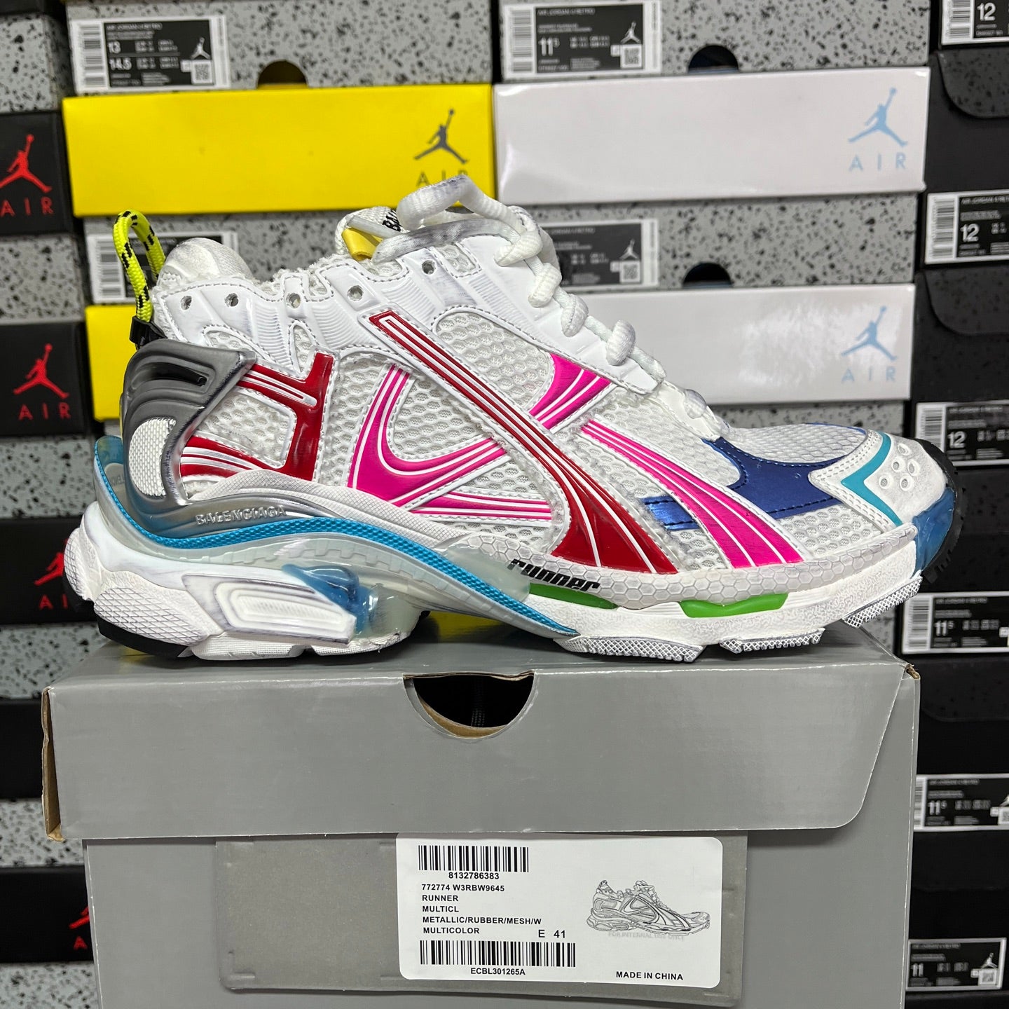 White lace-up sneakers with blue, red, and pink side stripes and chunky sole