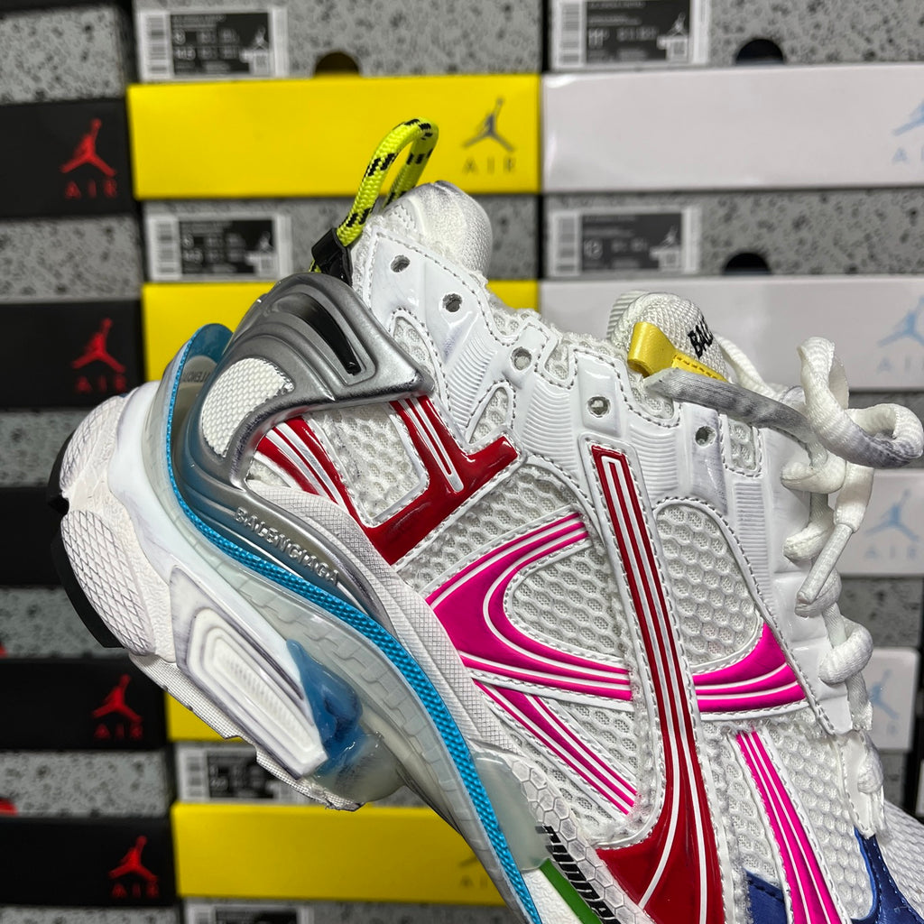 White sneaker with blue, red, and pink stripes, gray heel cage, chunky sole
