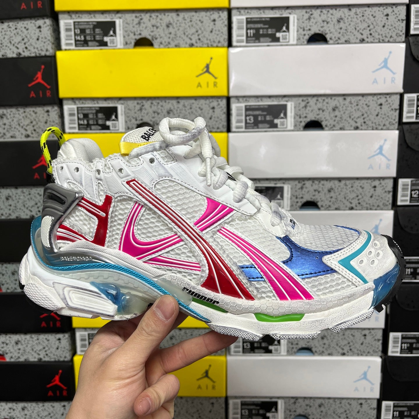 White lace-up sneakers with blue, red, and pink striped panels, sporty sole