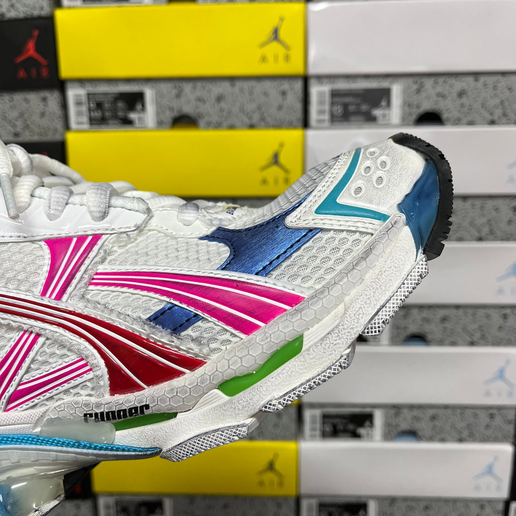 White sneaker side profile with blue, pink, and red accents and textured mesh