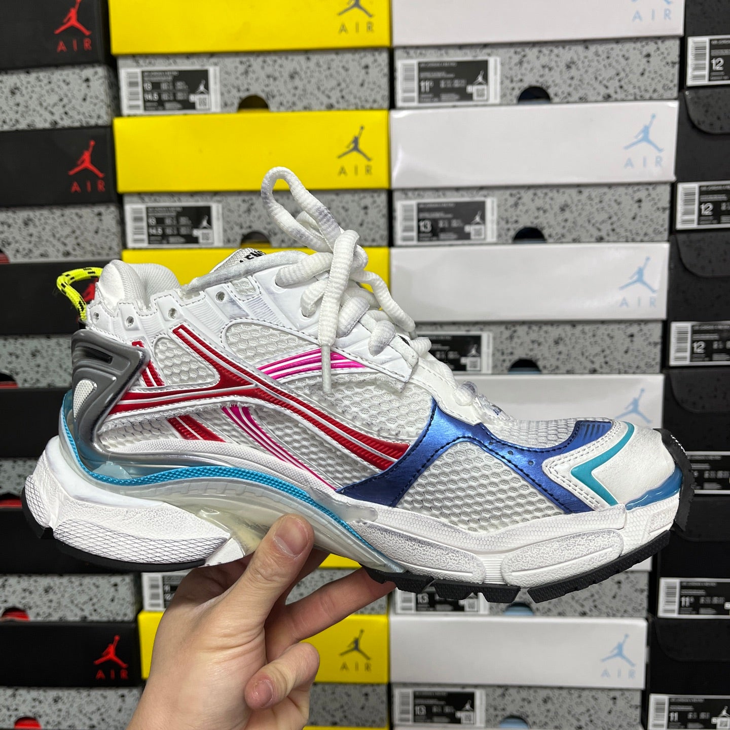White lace-up sneakers with blue, red, and pink accents and chunky sole