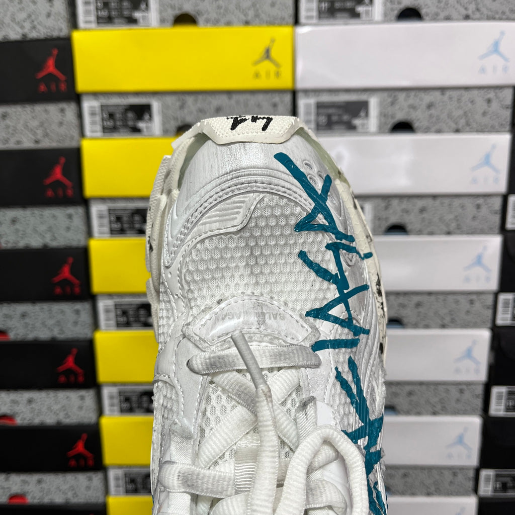 White sneaker heel with teal-blue branding and textured upper panels.
