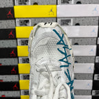 White sneaker heel with teal-blue branding and textured upper panels.