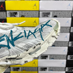 White sneaker toe and side with teal-blue logo and cushioned rubber sole.