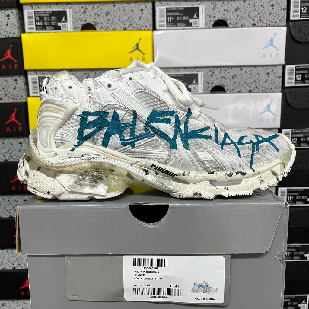 White sneaker with teal-blue side graphic and chunky molded rubber sole.