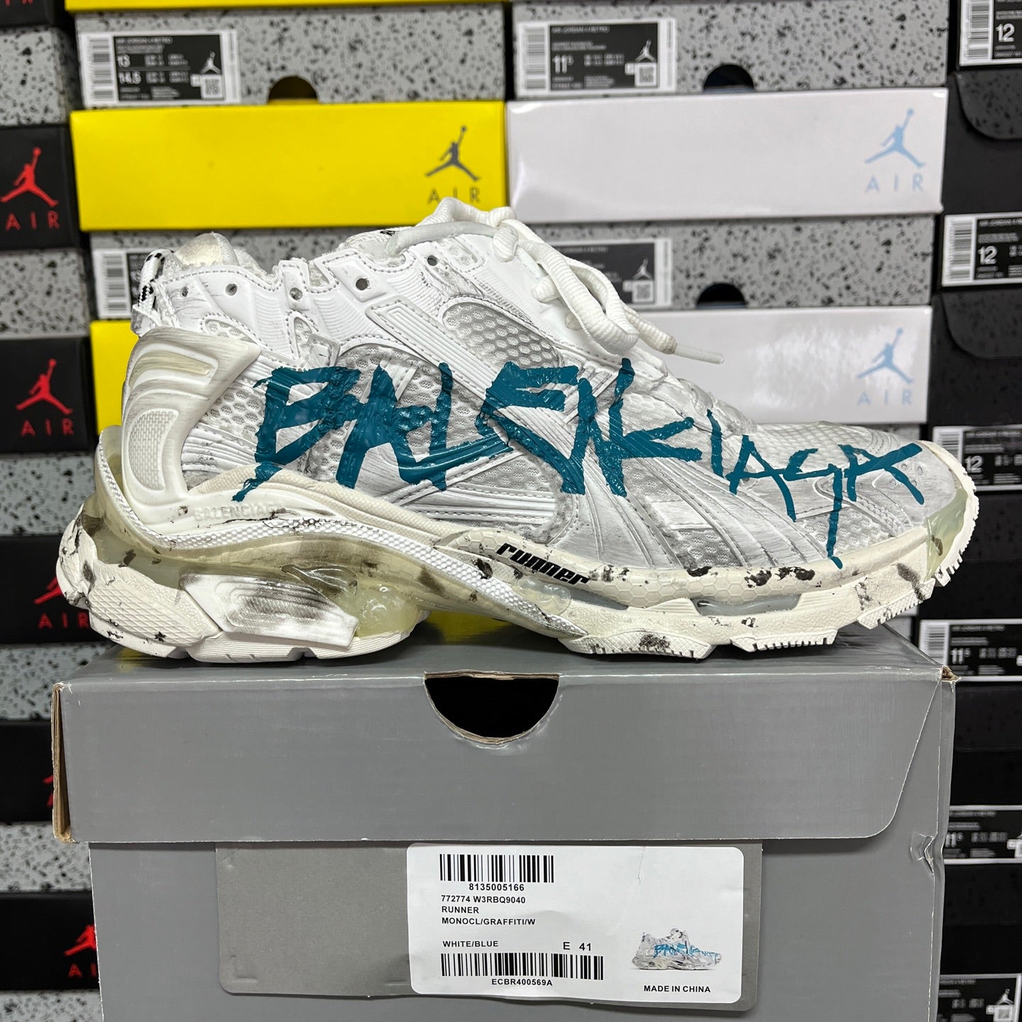 White sneaker with teal-blue side graphic and chunky molded rubber sole.