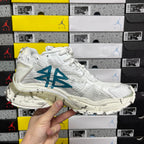 White sneaker with teal-blue side logo and lace-up design on textured upper.