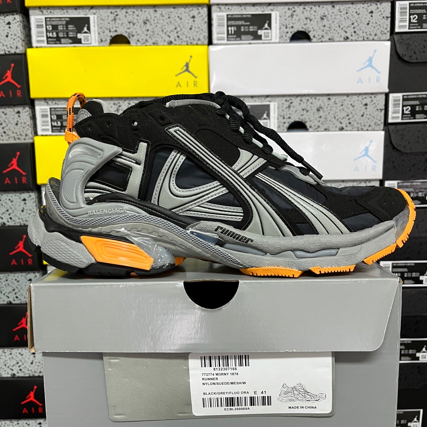 Balenciaga unisex sneaker with black upper, gray stripes, orange edge sole