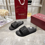 Black slide sandals with embossed GG logo on the front strap and wide footbed