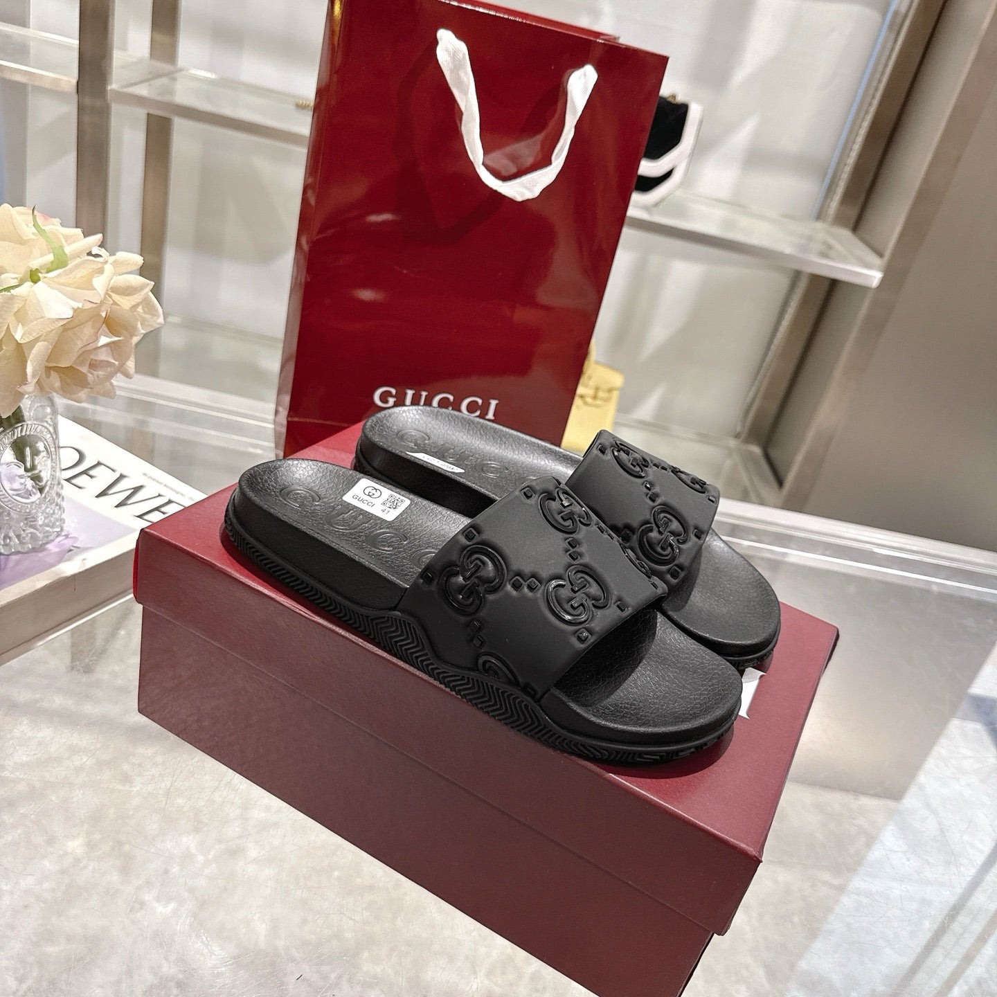 Black Gucci slide sandals with embossed GG pattern on the strap and footbed