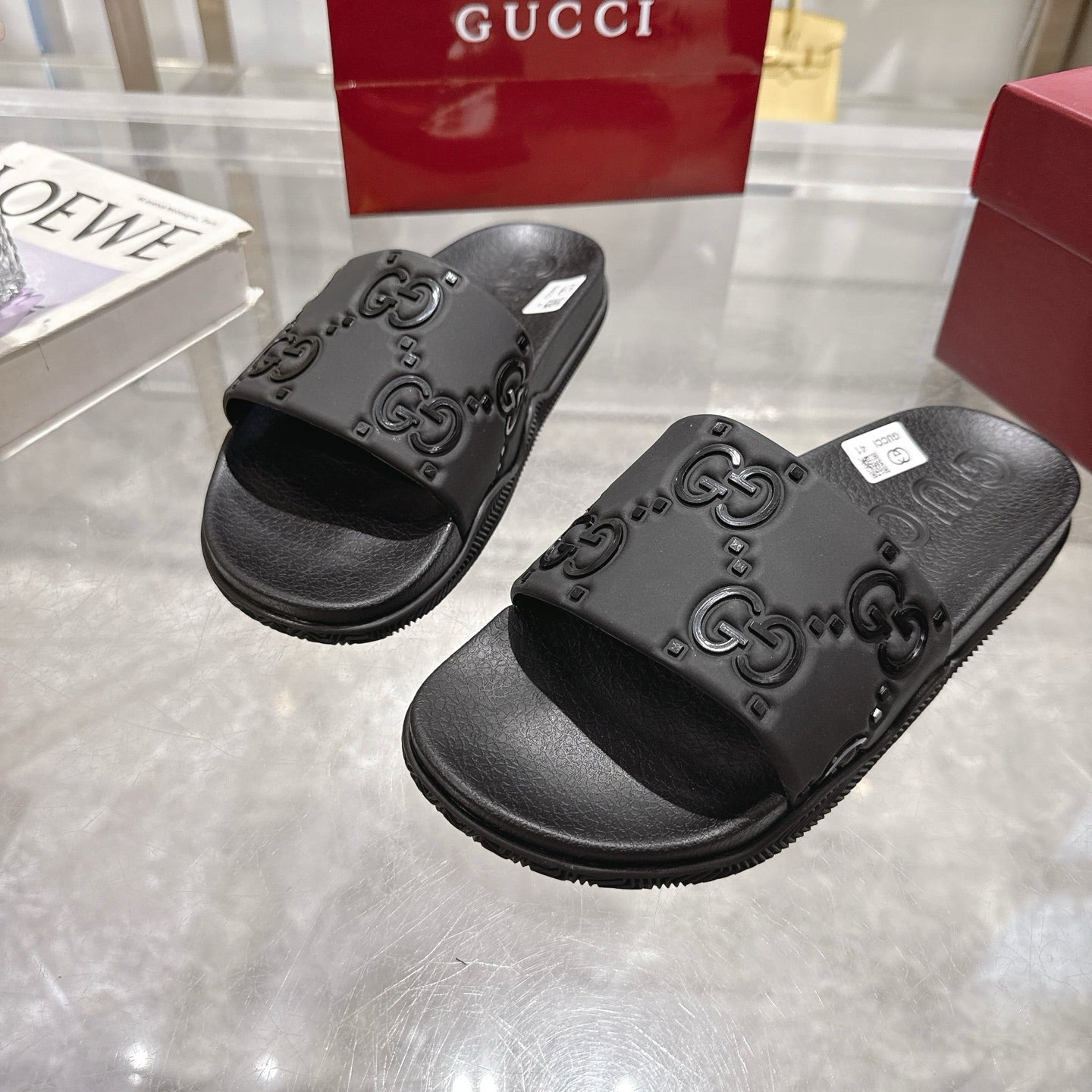 Black Gucci slide sandals with detailed GG embossing on the foot straps, close view