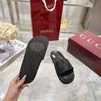 Black slide sandals showing textured outsole and embossed logo on the underside