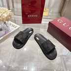 Black Gucci slide sandals with embossed signature GG pattern, angled pair view