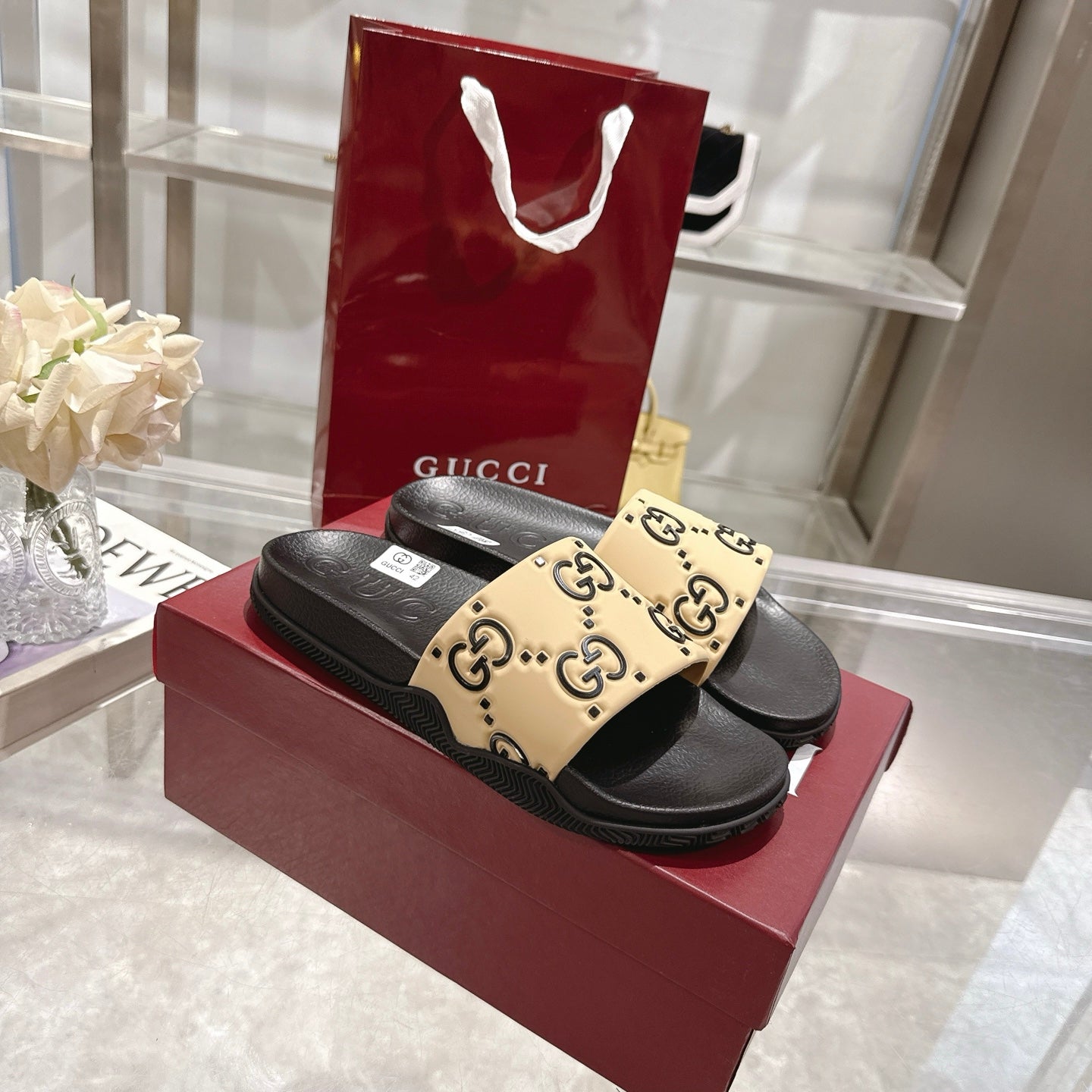 Gucci slide sandals with black footbed and beige GG logo patterned strap