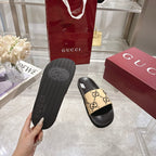 Back view of black slide sandal sole with circular GG logo, beige strap
