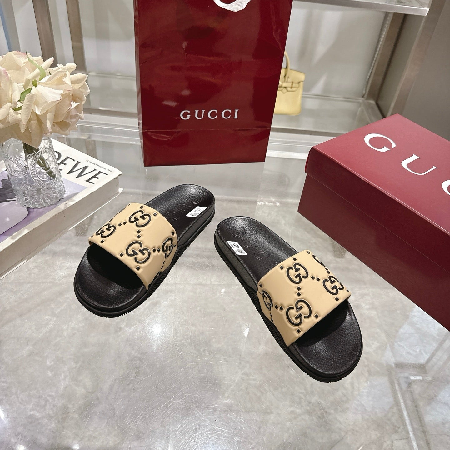 Gucci slide sandals with black rubber soles and beige GG monogram strap panels