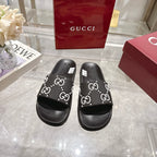 Gucci black slide sandals with white GG logo band over open toe