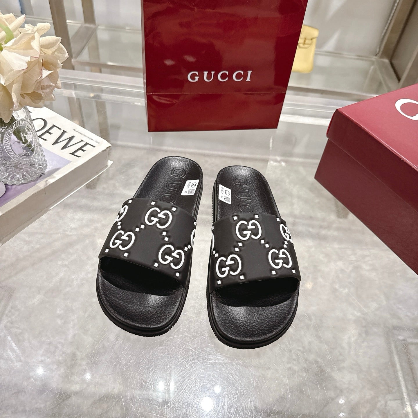 Gucci black slide sandals with white GG logo band over open toe
