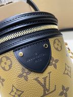 Louis Vuitton bag close-up of black leather trim with gold zipper hardware and logo patch