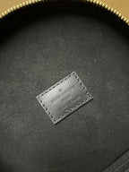 Louis Vuitton bag close-up of interior label on dark fabric with gold zipper rim