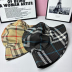 Two plaid bucket hats: one beige with multicolor checks, one black with blue checks