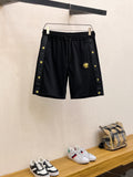 Black Versace-style shorts with drawstring waist and gold crest emblems on sides