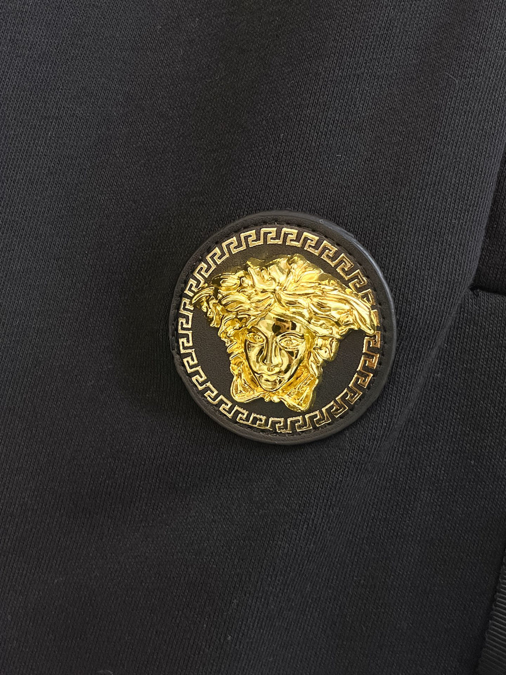 Gold crest emblem patch on black shorts front