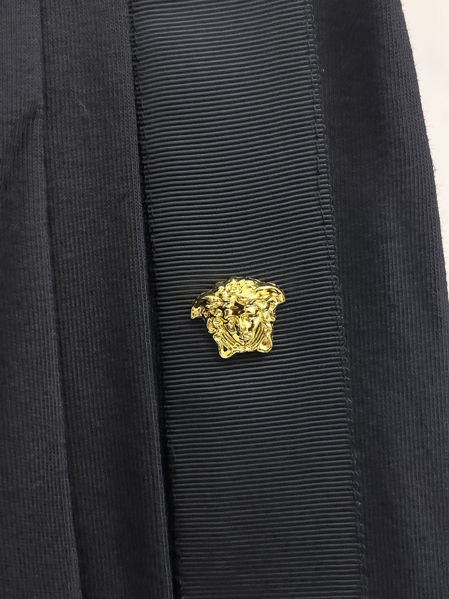 Gold crest emblem on black shorts side panel near pocket