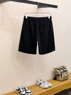 Black shorts with elastic waistband and small gold crest emblems