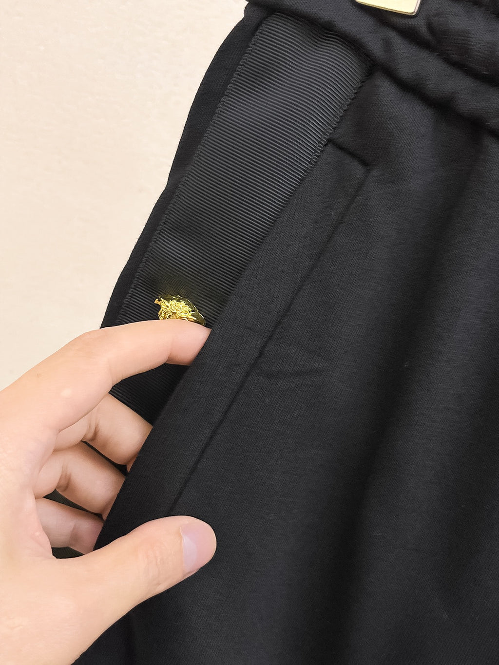 Black shorts fabric detail with gold crest emblem on side seam