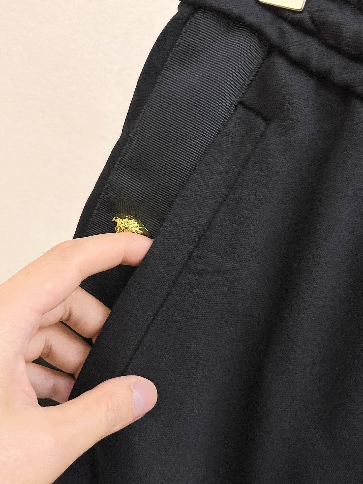 Black shorts fabric detail with gold crest emblem on side seam