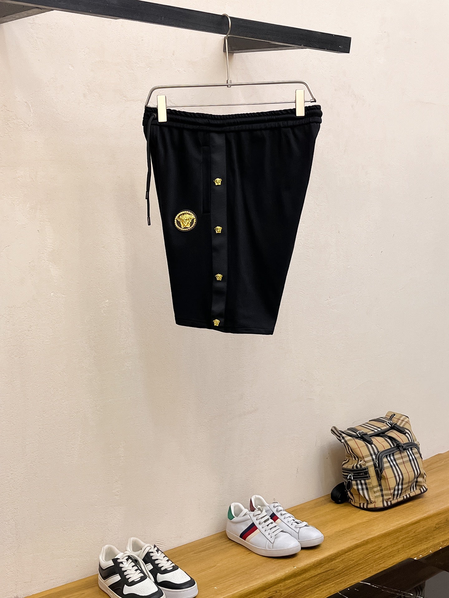 Black shorts on hanger with drawstring waist and gold crest emblem details