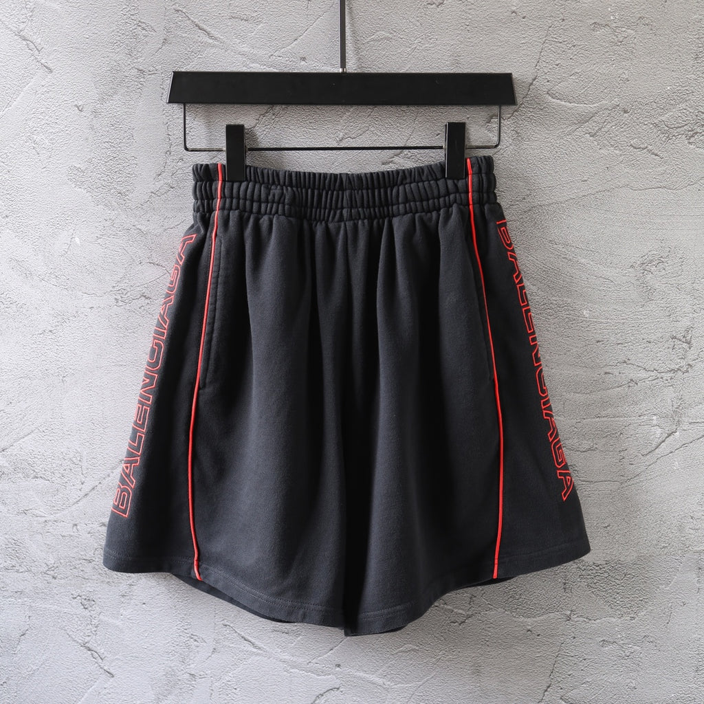 Black Balenciaga shorts with red side stripe and elastic waistband, relaxed fit.